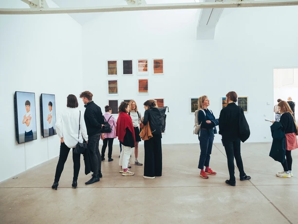 Photoszene-Festival_2.jpg Menschen betrachten Fotografien in heller Galerie mit großformatigen und kleinen Wandwerken