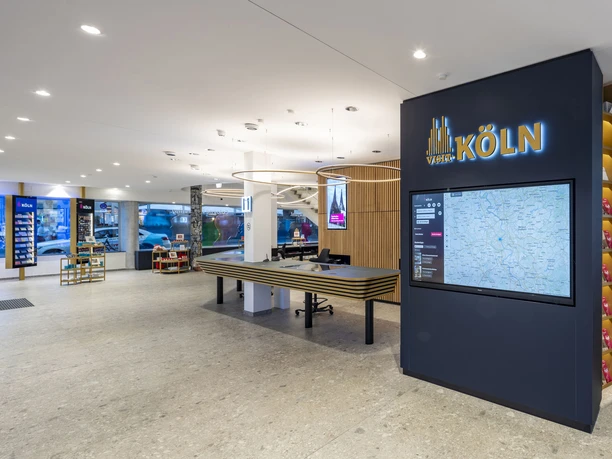Tourist Information Köln Innenansicht der modernen Touristeninformation Köln mit Empfangstresen und interaktivem Informationsdisplay.