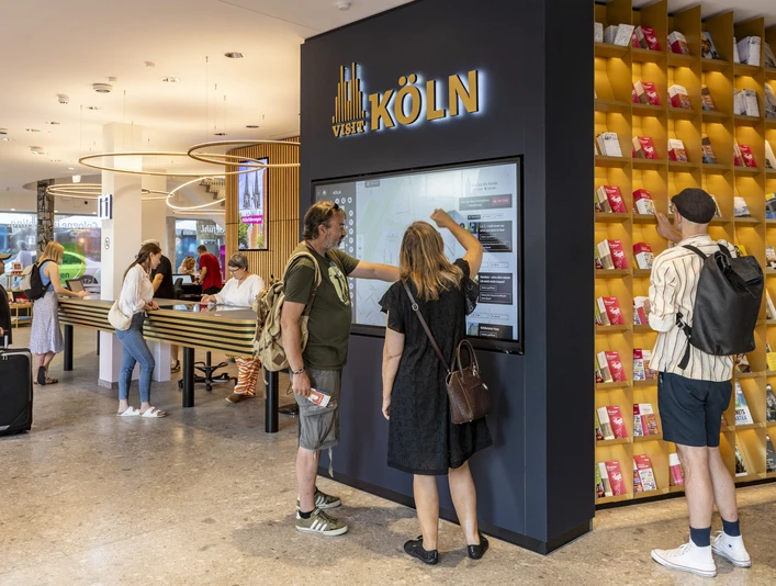 Tourist Information Köln Besucher nutzen interaktive Bildschirme in einer modernen Touristeninformation in Köln.Tourists interact at an info terminal inside a spacious, modern Cologne visitor centre.
