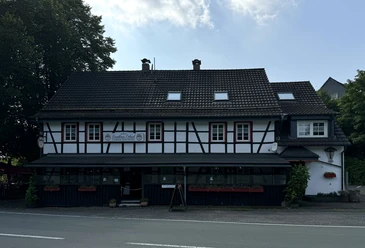Landhaus Orbach Außenansicht Historisches Fachwerkhaus mit Blumen geschmückter Fassade und einem bewirteten, einladenden Außenbereich.