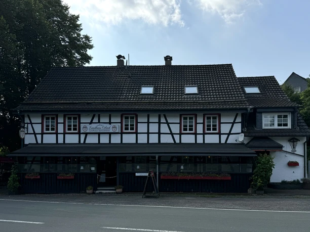 Landhaus Orbach Außenansicht Historisches Fachwerkhaus mit Blumen geschmückter Fassade und einem bewirteten, einladenden Außenbereich.