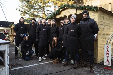 fabian stuertz 2022.12.15 - street kitchen 0005.jpg Teamfoto von Street-Kitchen Catering vor Holzständen für einen Weihnachtsmarkt