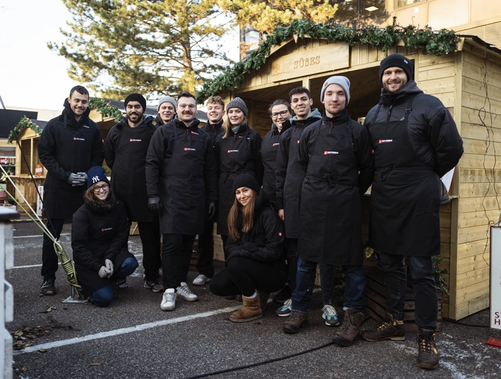 fabian stuertz 2022.12.15 - street kitchen 0005.jpg Teamfoto von Street-Kitchen Catering vor Holzständen für einen WeihnachtsmarktTeam photo of Street-Kitchen Catering in front of wooden stalls for a Christmas market