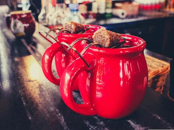 Feuerzangenbowle.jpg Zwei rote Tassen mit Feuerzangenbowle stehen auf der ThekeTwo red cups of Feuerzangenbowle are standing on the counter.