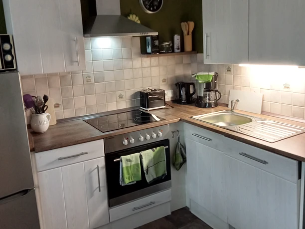 Küche in der Fewo Villa Neviges in Velbert-Neviges Helle Küche mit weißen Schränken, Herd, Spüle, Fliesenrückwand und moderner Ausstattung.