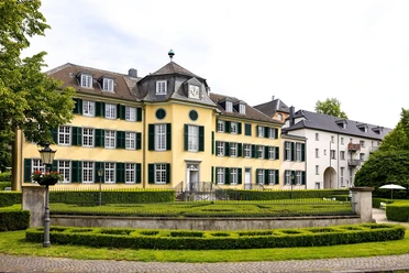 Herrenhaus Cromford Historisches Herrenhaus mit gelber Fassade, flankiert von grünen Fensterläden und gepflegter Gartenanlage.