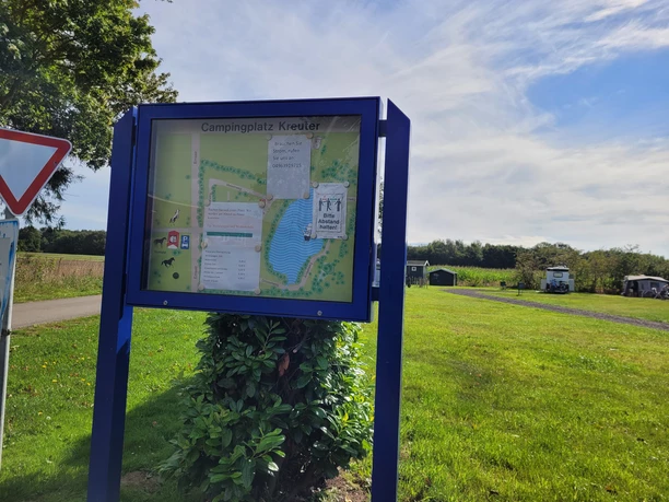 Campingplatz Kreuter Heede ©Emsland Tourismus GmbH (2).jpg Informationsschild des Campingplatzes Kreuter mit Lageplan, Wiese, Bäumen und Wohnmobil im Hintergrund
