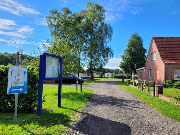 Campingplatz Kreuter Heede ©Emsland Tourismus GmbH (3).jpg Eingangsbereich eines Campingplatzes mit Infotafel, Weg, Grünflächen und roten Backsteingebäuden.