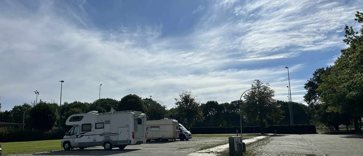 Wohnmobilstellplatz Sportzentrum Emspark Rhede ©Emsland Tourismus GmbH (2).JPEG Wohnmobilstellplatz mit gepflasterter Fläche, abgestellten Fahrzeugen und grünem Randbereich bei Sonnenschein