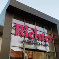 Nahaufnahme einer eckigen Fassade mit großen Glasflächen. Pinke Aufschrift: "Richter" darunter in blau: "Altstadtbäcker"