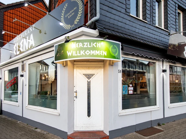 Exterior view of the restaurant, a large sign above the door: Welcome