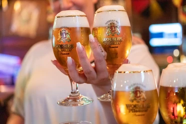 Frischgezapftes Bier in der Hand der Servicekraft