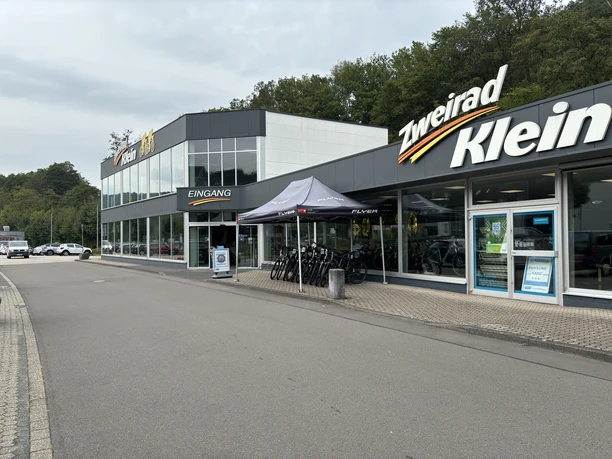 Zweirad Klein Zweiradgeschäft mit Fahrrädern vor dem Eingang und großen Fenstern, gelegen an einer ruhigen Straße.