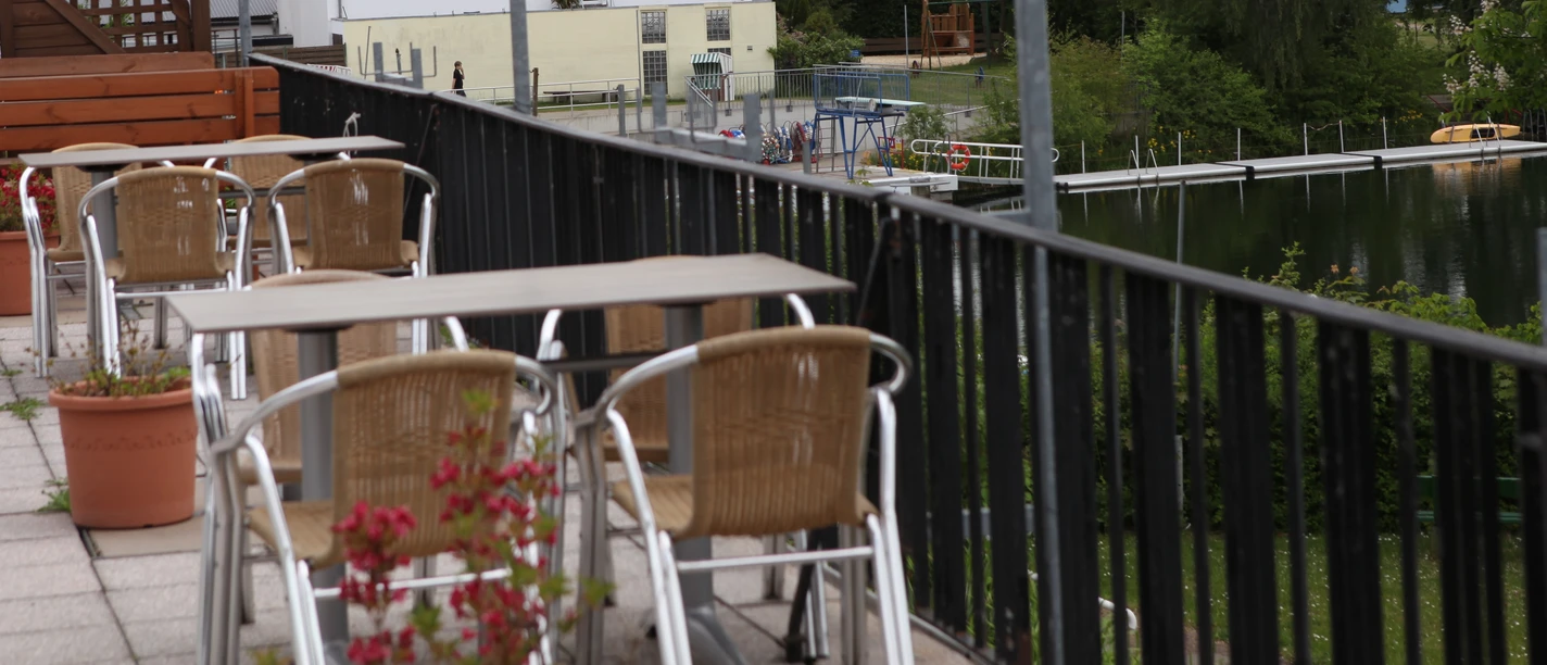 Fümmelsee Terrasen.JPG Tische und Stühle auf einer Terrasse, im Hintergrund ein See