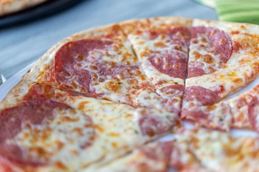L'Oliveto Pizza Nahaufnahme einer geschnittenen Salamipizza auf einem Teller