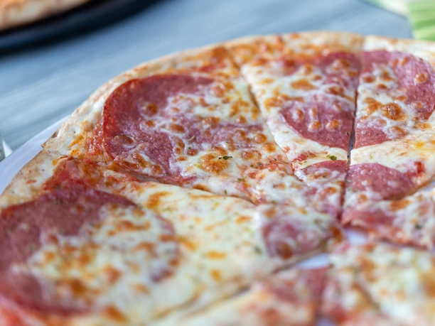 L'Oliveto Pizza Nahaufnahme einer geschnittenen Salamipizza auf einem Teller