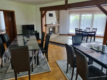 Ferienhaus Eggetal_Esszimmer Esszimmer mit dunklem Holztisch und lederbezogenen Stühlen, Kamin im Hintergrund, Blick ins Grüne.
