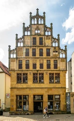 Bielefeld-Crüwell-Teutoburger-Wald-D-Ketz-124.jpg Historisches Gebäude mit reich verzierter Fassade, gelbem Stein und zahlreichen Fenstern. Vorne verläuft eine Straße.