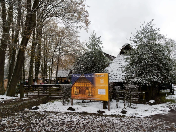 historischer-weihnachtsmarkt-bad-zwischenahn-eingang.jpg Toegang tot de historische kerstmarkt in Bad Zwischenahn met een besneeuwd vakwerkhuis.