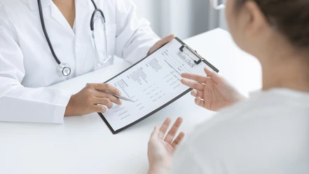 Badeärztin Inga Schmoor Symbolbild.png Auf dem Bild ist zu sehen, wie ein Arzt einem Patienten ein Formular zeigt und es ihm erklärt.