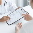 Badeärztin Inga Schmoor Symbolbild.png Auf dem Bild ist zu sehen, wie ein Arzt einem Patienten ein Formular zeigt und es ihm erklärt.