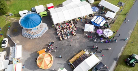 Drone shot of a fairground in Reinhardtsdorf with visitors, stalls and colorful bar tables.
