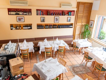 Gastraum in warmen Farben mit weiß gedeckten Tischen