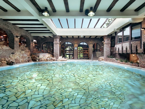 Neandertal Therme auf Land Gut Höhne in Mettmann Innenarchitektur einer Therme mit rustikalen Wänden, Oberlichtern und einem klaren, mosaikartigen Pool.