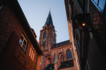 St. Nicolaikirche Lüneburg Blick durch eine schmale Gasse auf den Backsteinturm der St. Nicolaikirche in Lüneburg.