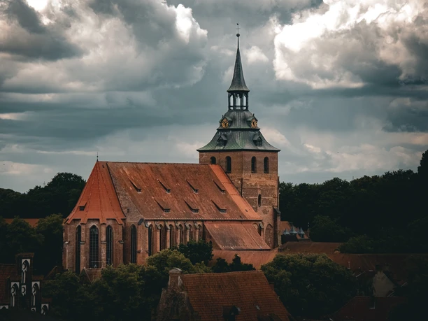 The large brick church of St. Michael in Lüneburg, with its striking tower, against a cloudy sky.