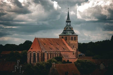 St. Michaeliskirche Lüneburg Große Backsteinkirche St. Michaelis in Lüneburg mit markantem Turm unter einem Wolkenhimmel.