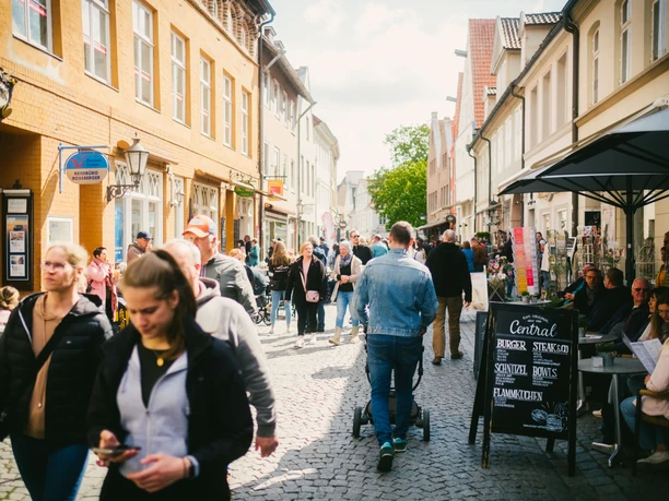 Buntes Treiben in der Schröderstraße zum Erlebnis-Sonntag Viele Personen am Erlebnis-Sonntag in der sonnigen Schröderstraße mit historischen Fassaden und Cafés.