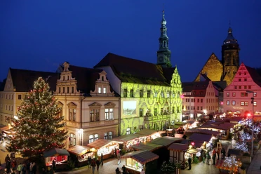 Der abendliche Canalettomarkt in Pirna, beleuchtet mit festlichen Lichtern und bunten Buden.