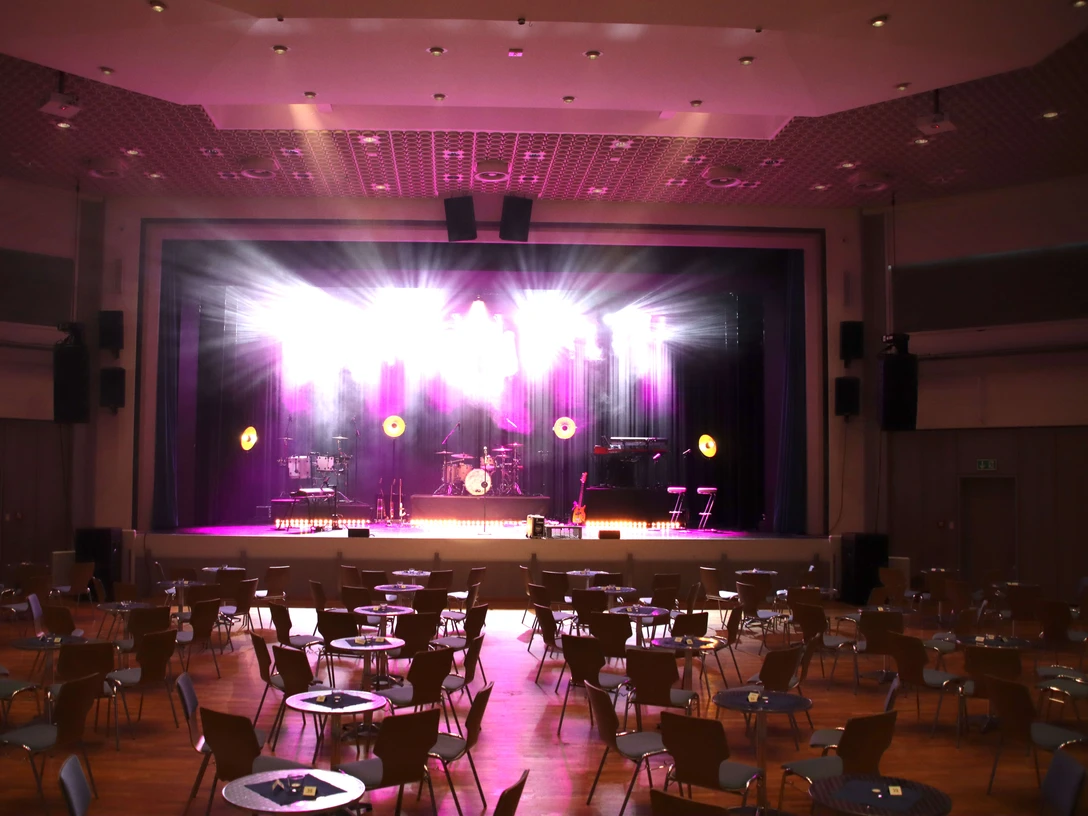 Delbrueck_Stadthalle_Bühne Saal mit großer Bühne, leuchtenden Scheinwerfern und Sitzplätzen; perfekt für Veranstaltungen.