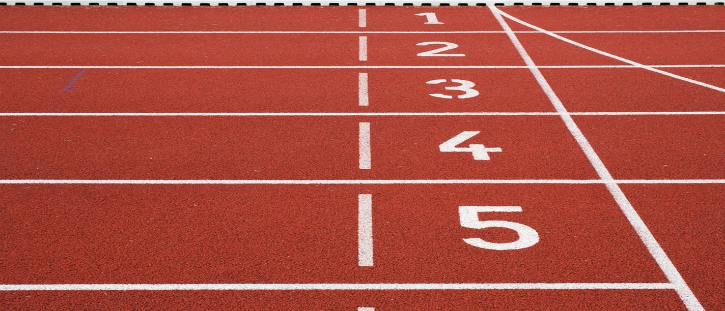 Laufbahn | Beispielbild Rote Tartanbahn mit sechs nummerierten Startlinien in einem Stadion für Leichtathletikveranstaltungen.