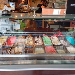 Eine bunte Auswahl an Eissorten in verschiedenen Farben und Geschmäckern hinter einer Glasvitrine.