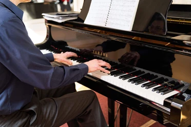 kurkonzert-bad-zwischenahn Musiker spielt am schwarzen Flügel im Kurhaus Bad Zwischenahn ein klassisches Konzertstück.