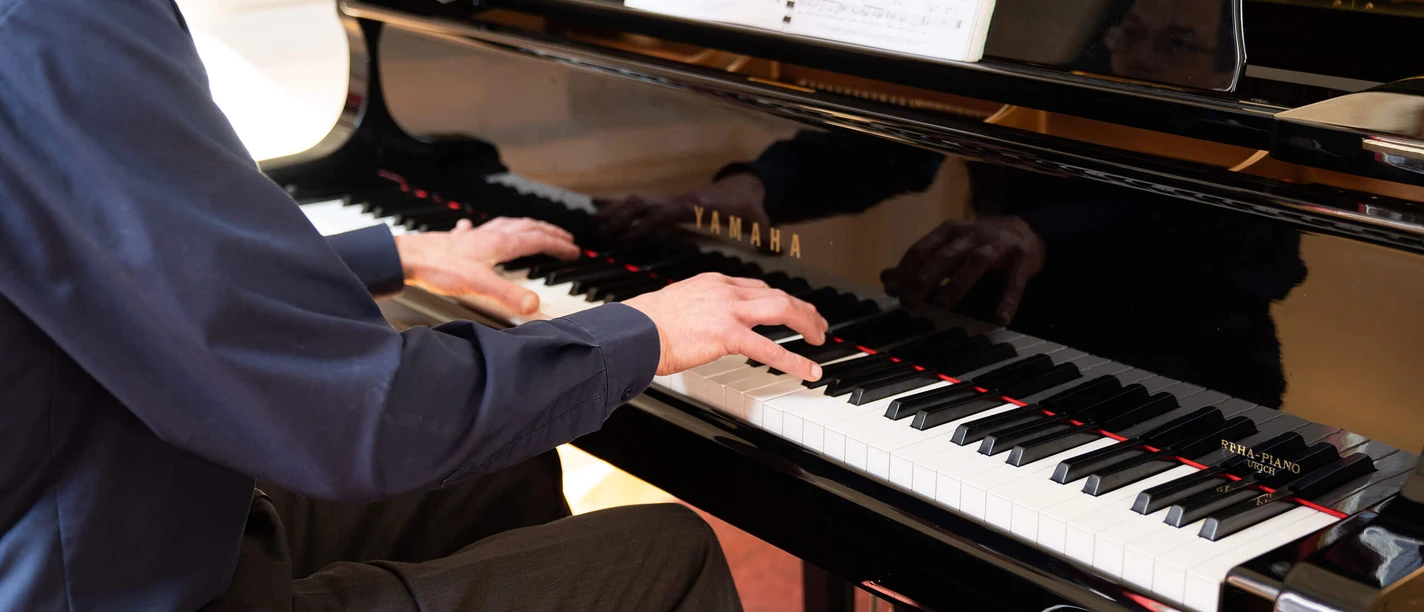 kurkonzert-bad-zwischenahn Musiker spielt am schwarzen Flügel im Kurhaus Bad Zwischenahn ein klassisches Konzertstück.