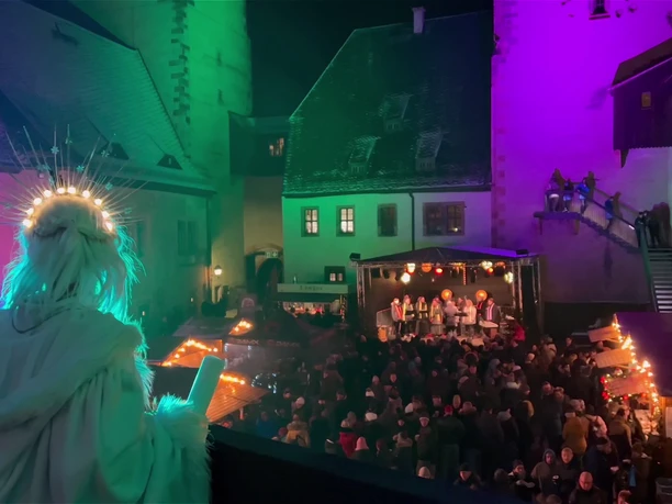 Rochlitzer Schlossweihnacht Zusehen ist der Innenhof von Schloss Rochlitz mit der Schlossweihnacht. Am Bildrand ist ein Engel.