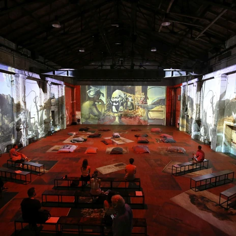 Interior view of the Kunstkraftwerk Leipzig with projections and seating on the floor.