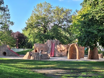12 - Supervulkan-Zentrum R├Âcknitz - Spielplatz Fred Porphyrstein - Foto Kathleen Schramm.jpg Abenteuerspielplatz mit Kletterstrukturen aus Steinimitat unter schattigen Bäumen.Adventure playground with climbing structures made of imitation stone under shady trees.Dobrodružné hřiště s prolézačkami z imitace kamene pod stinnými stromy.Przygodowy plac zabaw z konstrukcjami wspinaczkowymi wykonanymi z imitacji kamienia pod zacienionymi drzewami.Avonturenspeeltuin met klimstructuren van imitatiesteen onder schaduwrijke bomen.Parco giochi avventuroso con strutture per l'arrampicata in finta pietra sotto alberi ombrosi.