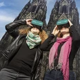 TimeRide VR cathedral tour Two people enjoy an immersive tour with VR glasses in front of Cologne Cathedral.