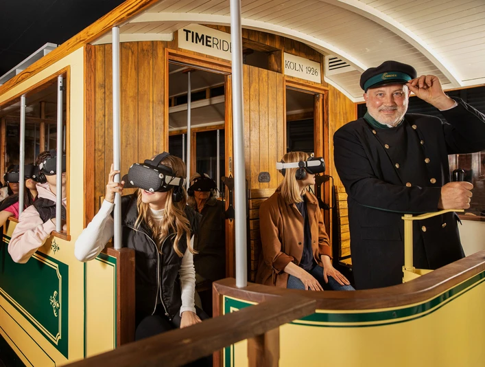 Timeride SENSEUM Personen in einer historischen Straßenbahn tragen VR-Brillen und erleben eine virtuelle Zeitreise.People in a historic streetcar wear VR glasses and experience a virtual journey through time.