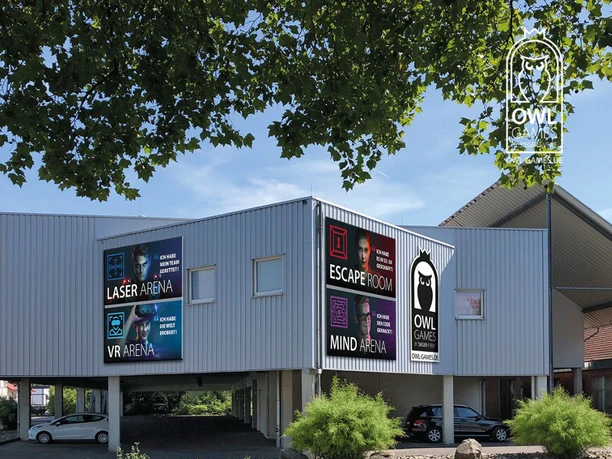 Außenansicht OWL Games Zweistöckiges Gebäude mit auffälligen Werbeschildern für Laser Arena, Escape Room und mehr.