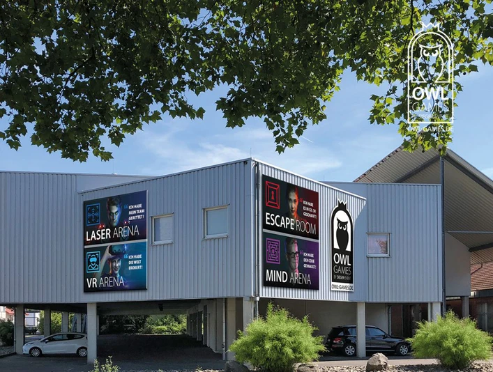 Außenansicht OWL Games Zweistöckiges Gebäude mit auffälligen Werbeschildern für Laser Arena, Escape Room und mehr.