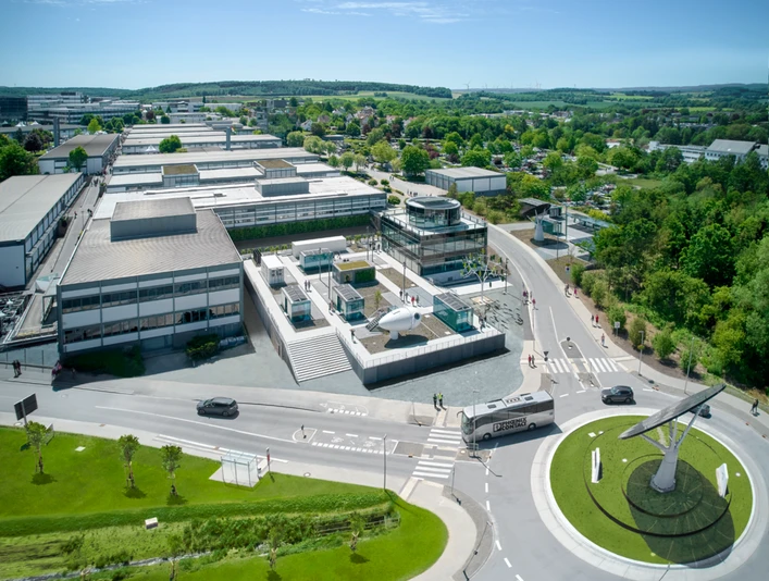 Luftaufnahme des All Electric Society Parks in Blomberg mit Gebäudekomplex und grünem Umland.