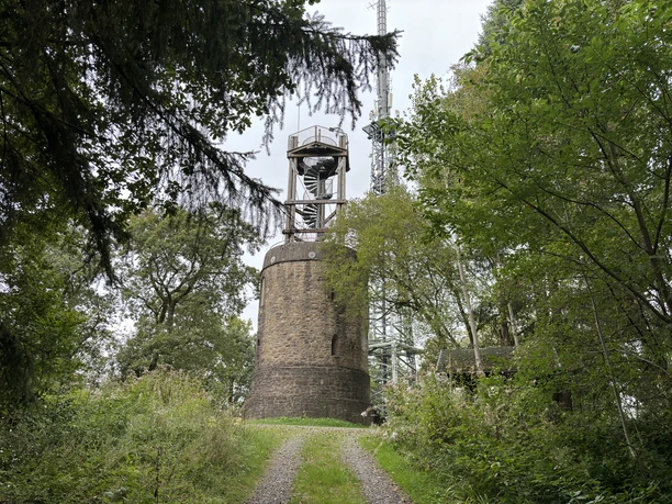 Aussichtsturm Hohe Warte <p>Alte Steinturmruine in einem bewaldeten Gebiet mit modernen Antennenstrukturen im Hintergrund.</p>