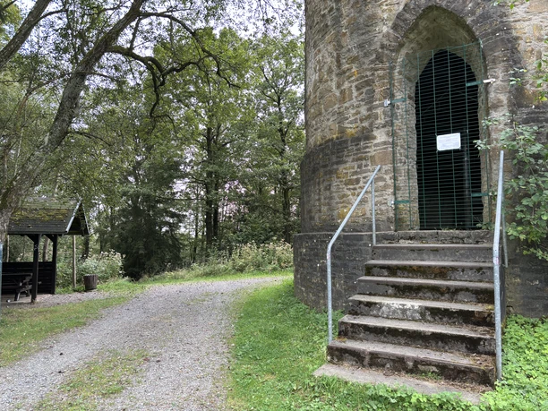Aussichtsturm Hohe Warte Steinerner Turm mit Metalldach, umgeben von Bäumen; Treppen und Kiesweg führen dorthin.