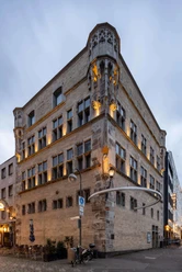 Haus Saaleck, artothek Historisches Gebäude mit verzierten Ecktürmen, mehrstöckigen Fenstern und Abendbeleuchtung.