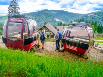 Wanderer an den Liftgondeln bei der Raststation s´alte Lifthisli am Kernhof mit Blick zur Hornisgrinde